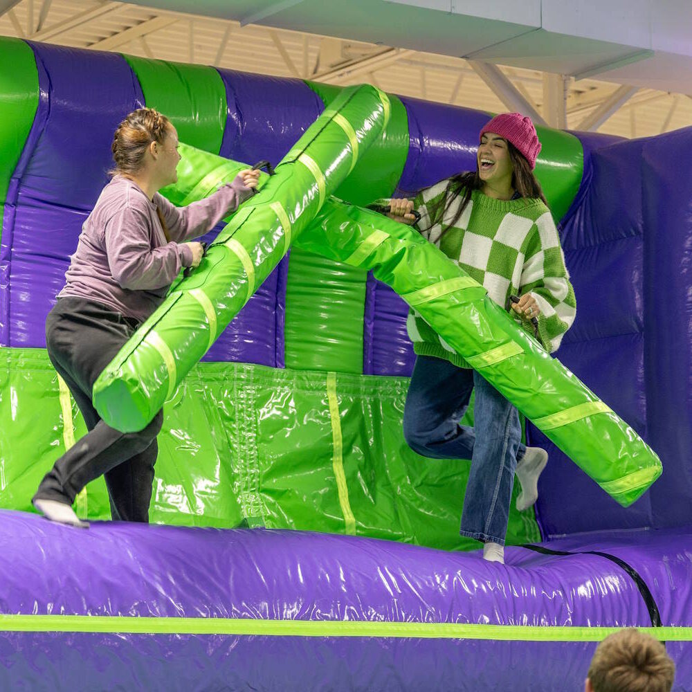 two teenagers playing in an inflatable jousting area
